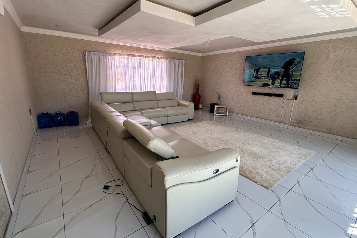 Spacious living room featuring modern marble-look floor tiles, a decorative recessed ceiling design, and textured wall finishes.