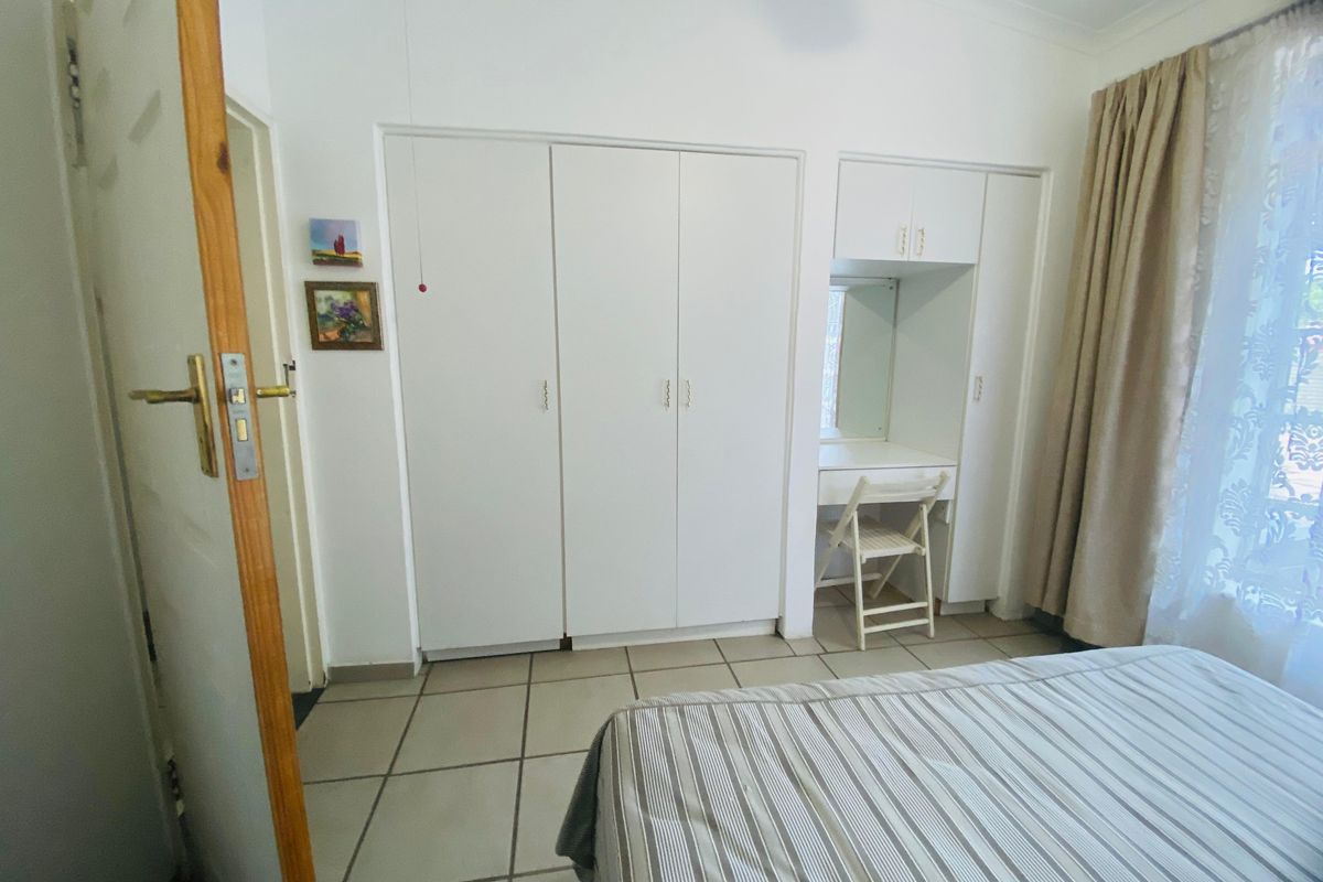 A bedroom featuring built-in cupboards with an integrated vanity unit and tiled flooring.