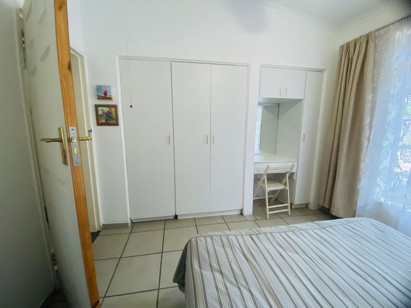 A bedroom featuring built-in cupboards with an integrated vanity unit and tiled flooring.