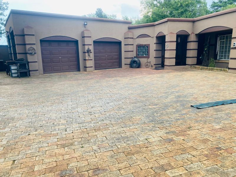 Front exterior view of the property featuring a paved driveway, double garage doors, and a covered entrance area.
