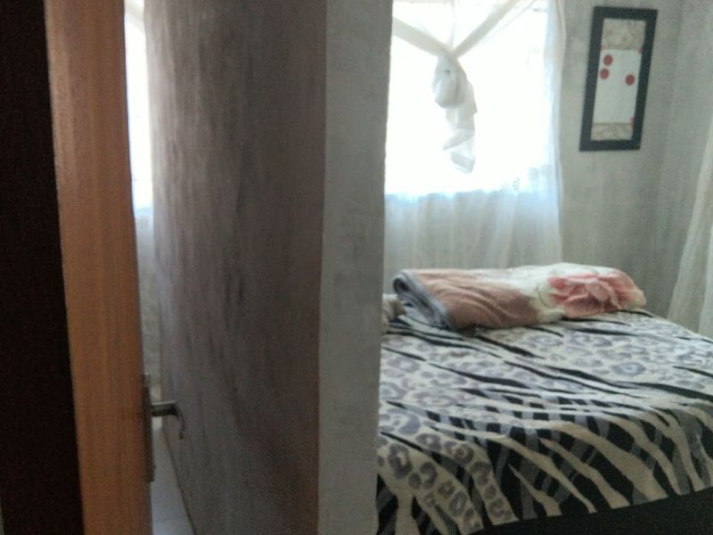 A bedroom featuring tiled flooring and a window, viewed from the doorway.