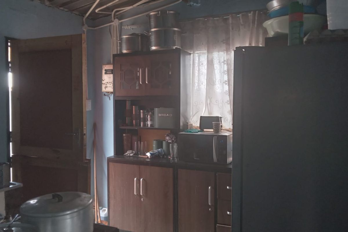 A functional kitchen area featuring built-in wooden cabinetry, exposed ceiling conduit, and direct access to an exterior door.