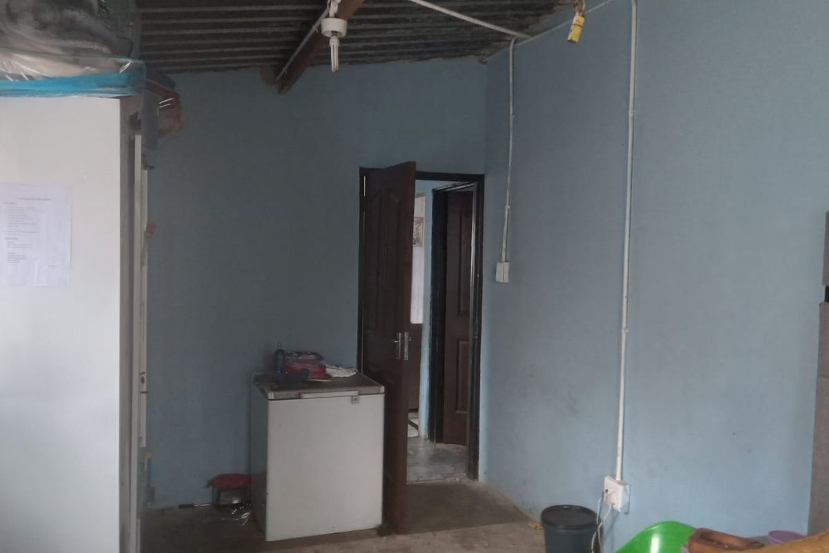 A basic bedroom interior featuring exposed electrical wiring, a simple door frame, and unfinished ceiling panels, requiring cosmetic updates and maintenance.
