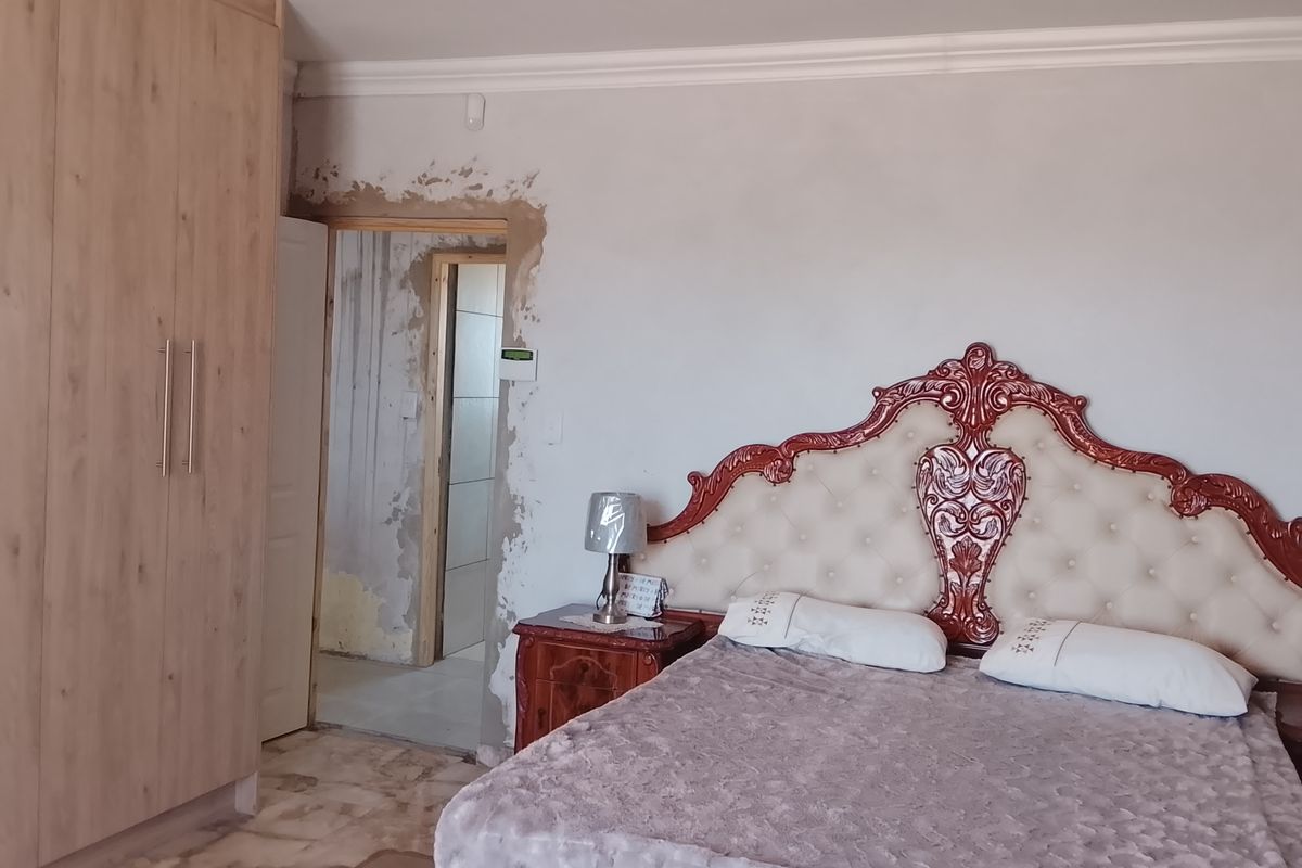 A bedroom featuring built-in wooden cabinetry and an ornate headboard, currently requiring finishing work on the wall surrounding the doorway.