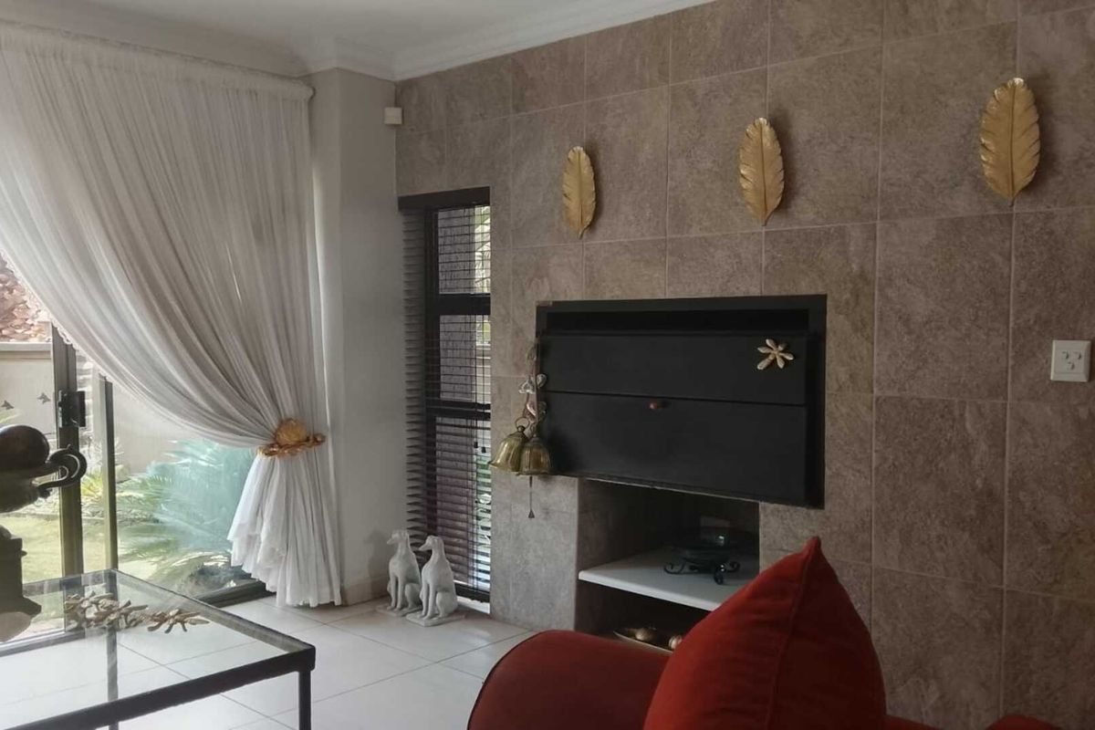 A living room featuring a tiled feature wall with a built-in fireplace and large sliding glass doors leading to the garden.