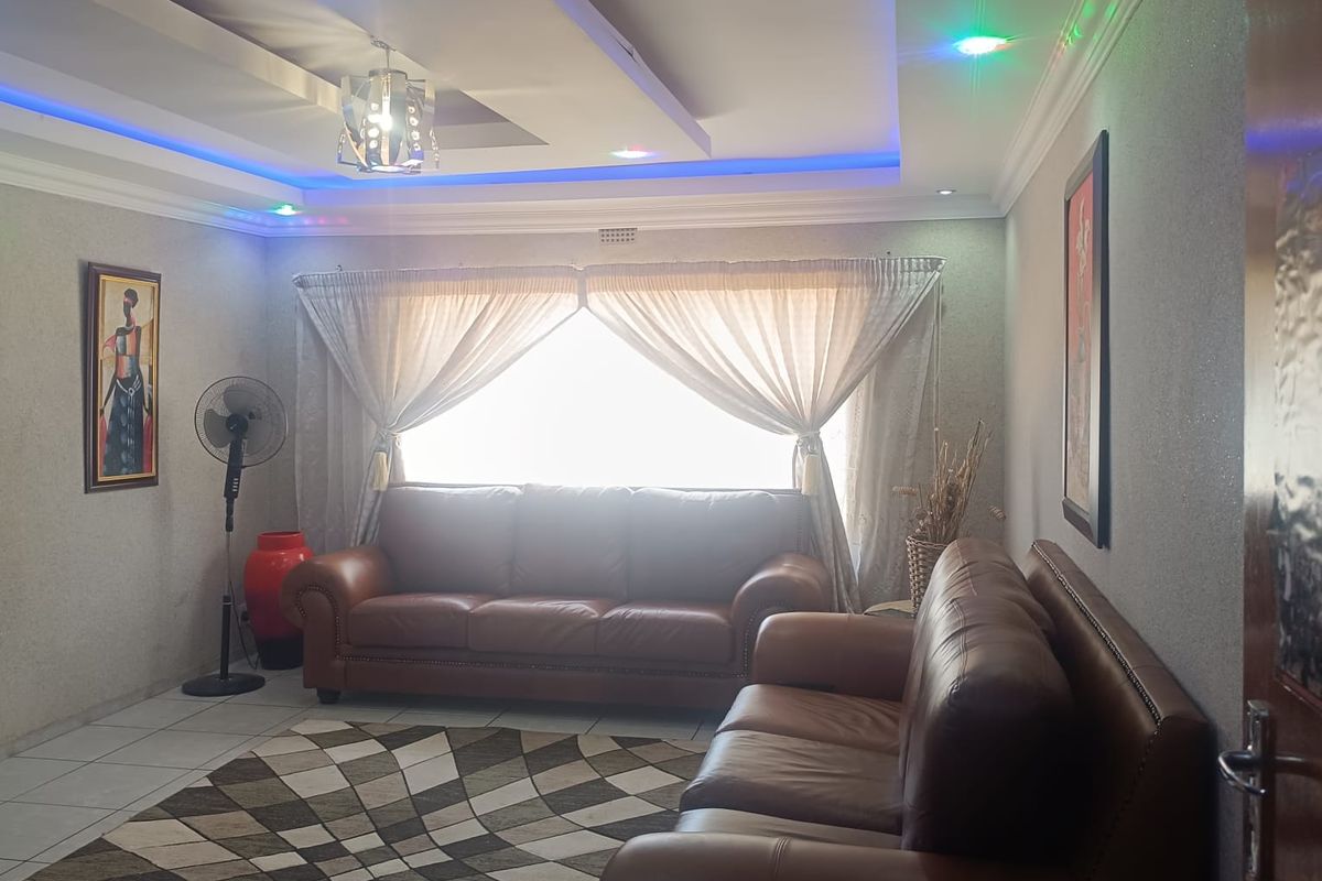 A living room featuring a recessed tray ceiling with integrated LED accent lighting and tiled flooring.