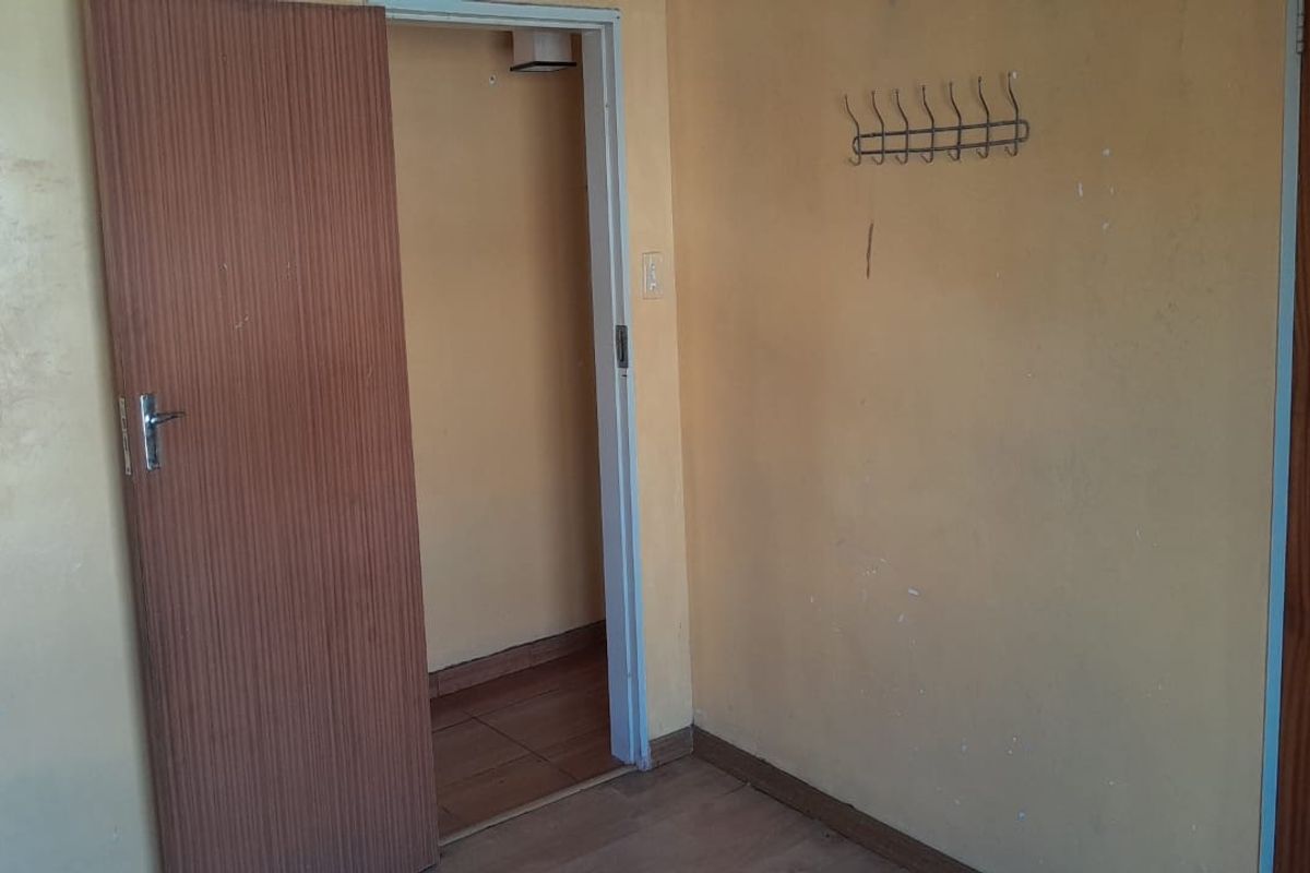 An interior view of a room featuring wooden doors and tiled flooring, showing signs of wear and requiring cosmetic updates.