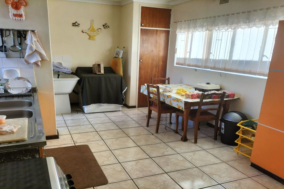 A functional kitchen and dining area featuring tiled flooring, a double stainless steel sink, and built-in storage cabinetry.