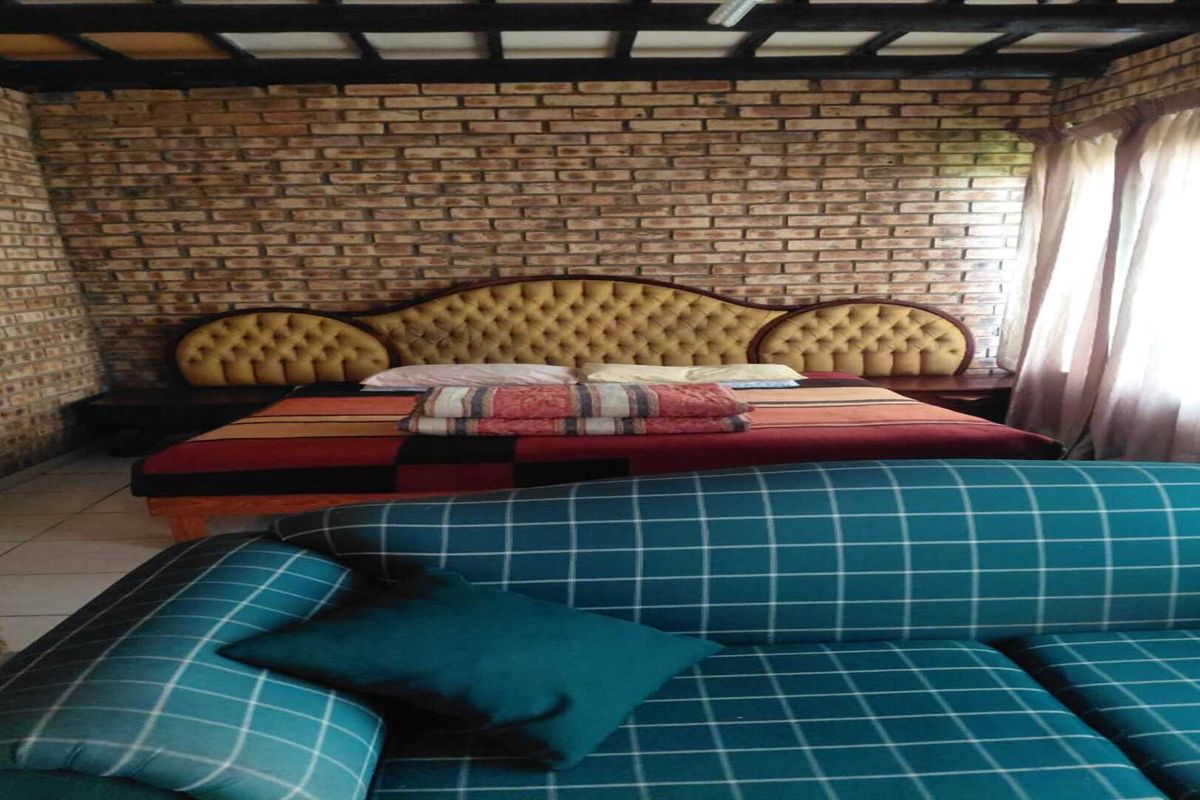 A bedroom featuring exposed brick walls and a dark timber beamed ceiling, creating a rustic aesthetic.