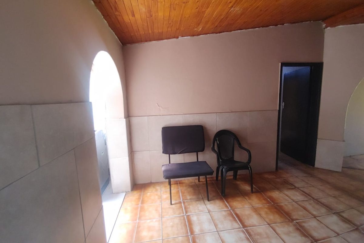 An interior space featuring tiled flooring, half-height wall tiling, and a timber-paneled ceiling with an arched doorway.