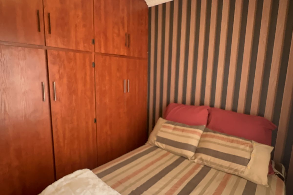 A bedroom featuring built-in wooden cabinetry and decorative striped wallpaper.