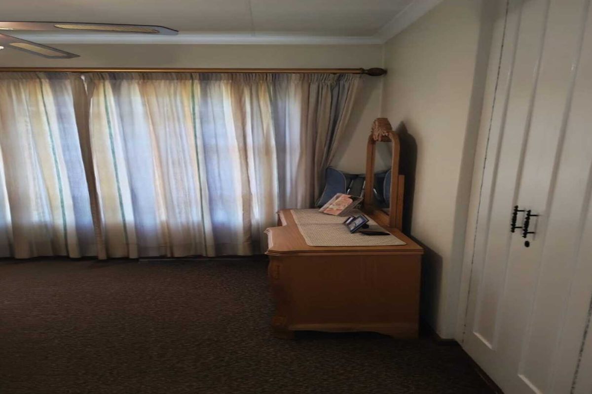 A bedroom featuring carpeted flooring, a ceiling fan, and built-in closet storage.