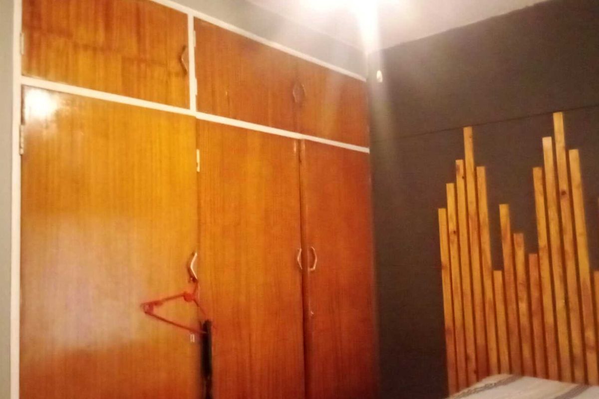 A bedroom featuring built-in wooden cabinetry with overhead storage and a decorative timber wall feature.