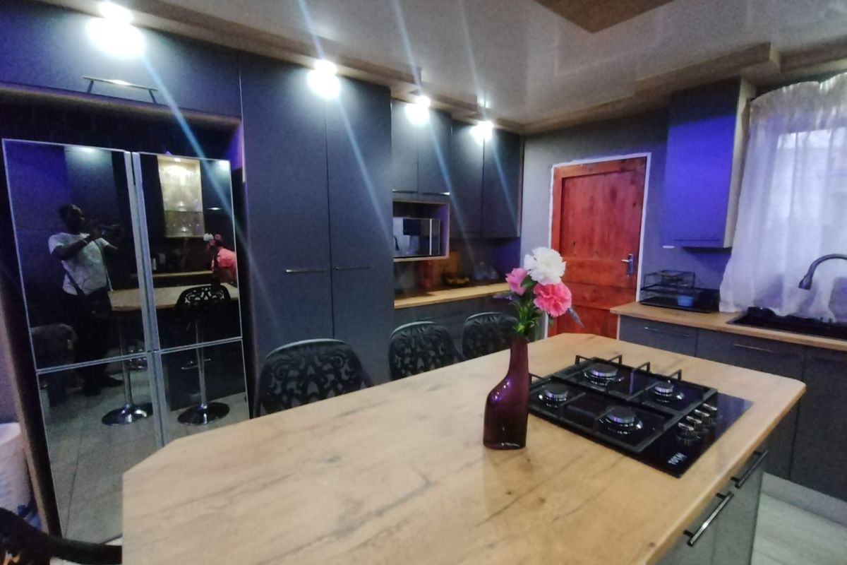 Modern kitchen featuring dark cabinetry, a central island with a built-in gas hob, and integrated storage solutions.