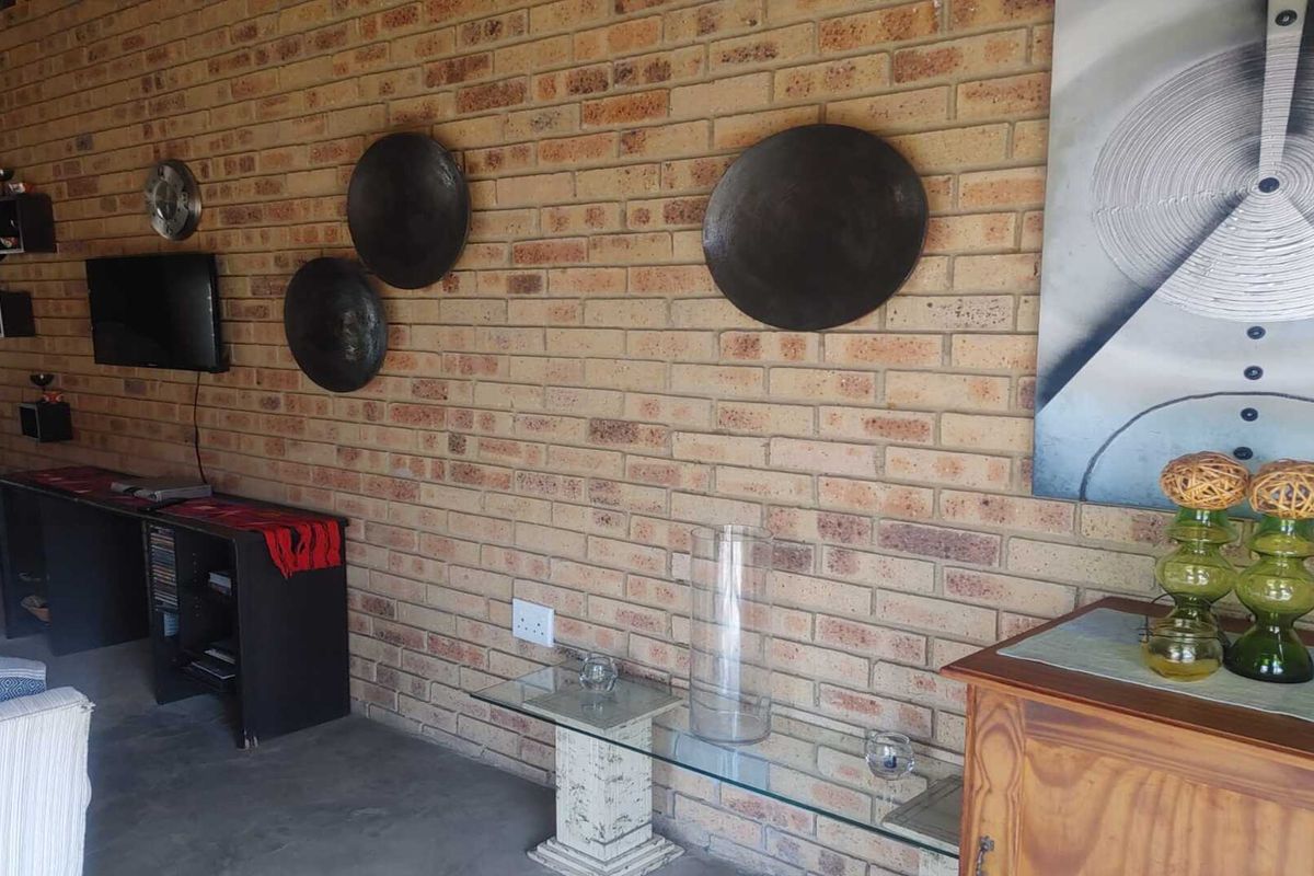 A living room featuring a prominent exposed face-brick feature wall and concrete flooring.