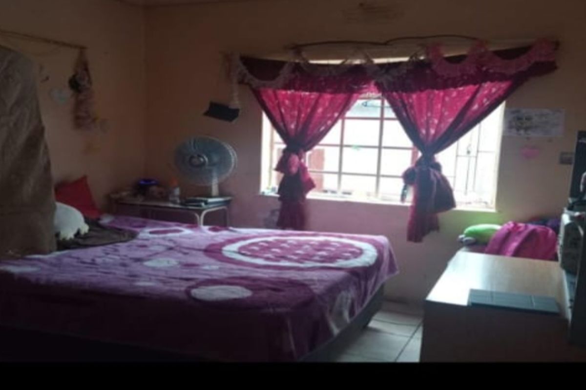 A bedroom featuring a window with security bars and tiled flooring.