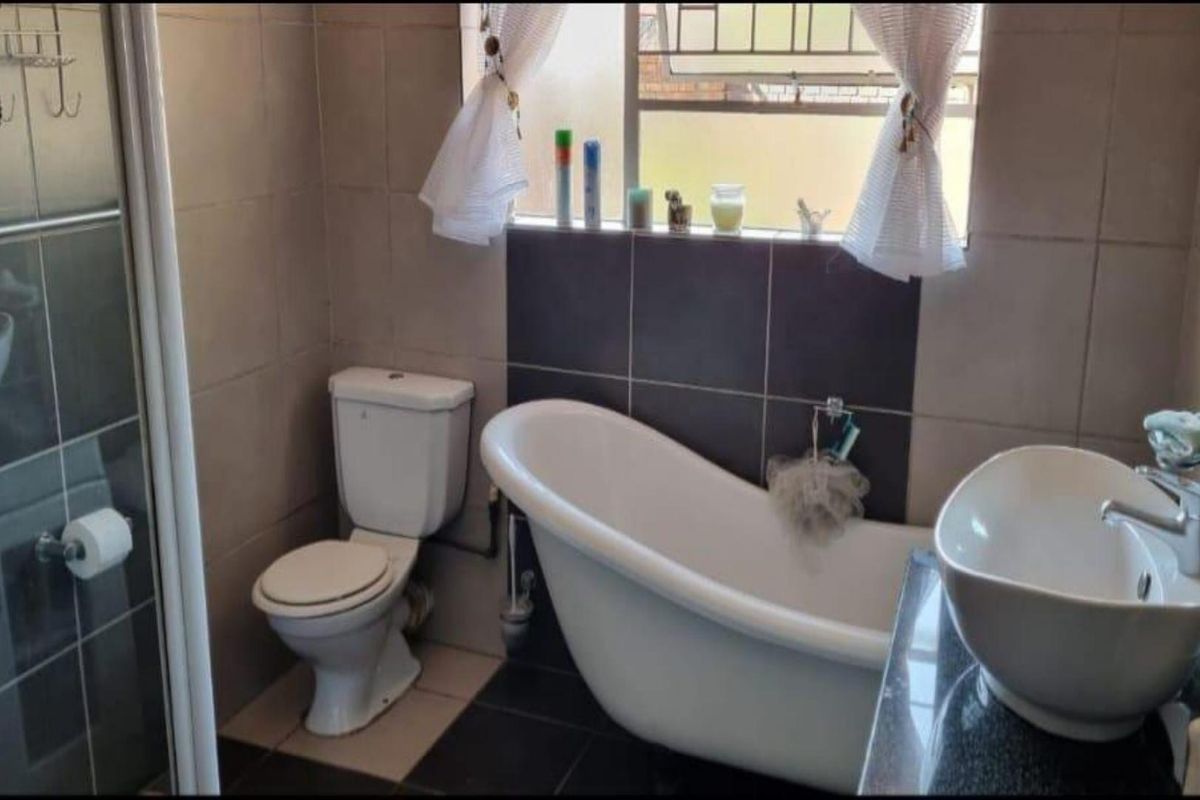 A functional bathroom featuring a freestanding bathtub, a separate glass-enclosed shower, a modern vessel sink, and a standard toilet with tiled walls.