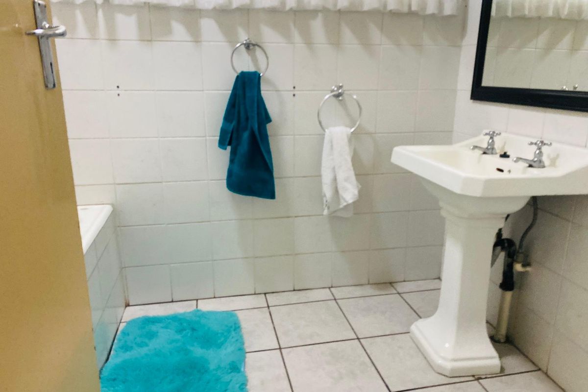 A functional bathroom featuring a pedestal sink, tiled walls, and a bathtub, offering a clean and practical layout.