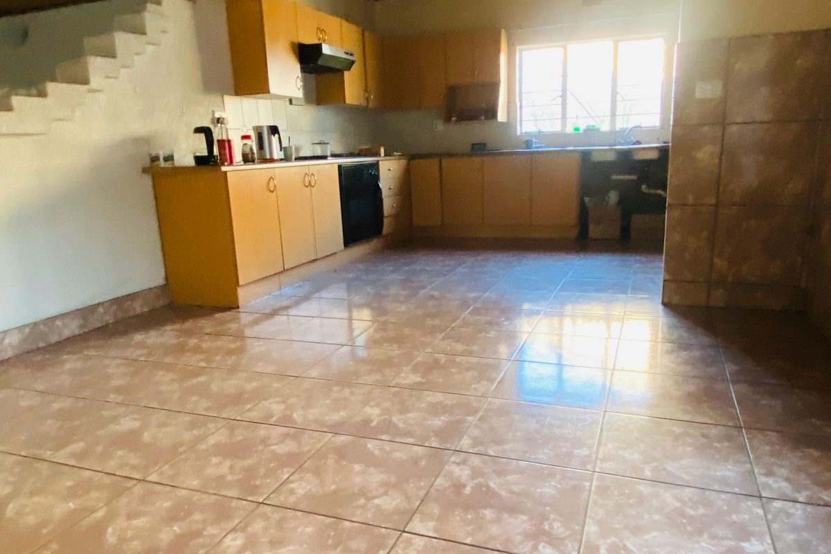 A dated kitchen featuring wooden cabinetry, tiled flooring, and a built-in oven, offering a functional layout with potential for modernization.
