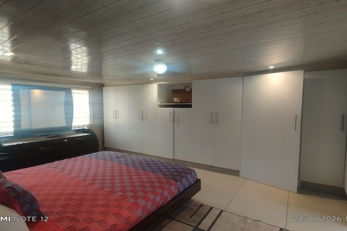 A bedroom featuring extensive built-in floor-to-ceiling cabinetry, tiled flooring, and a glossy panelled ceiling.