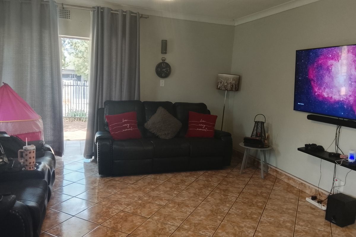 A comfortable living room featuring tiled flooring, a ceiling light fixture, and direct access to an outdoor patio area through a sliding glass door.