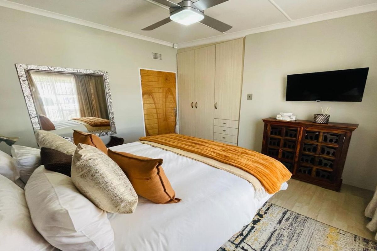 A well-maintained bedroom featuring built-in cupboards, a ceiling fan, and neutral wall finishes, providing a comfortable and functional living space.