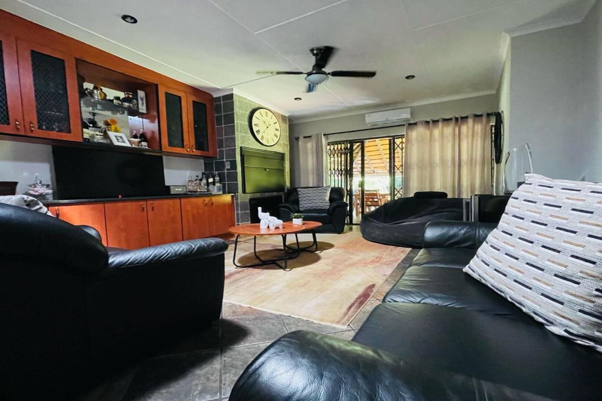 A comfortable living room featuring built-in wooden cabinetry, a ceiling fan, tiled flooring, and sliding door access to an outdoor patio area.