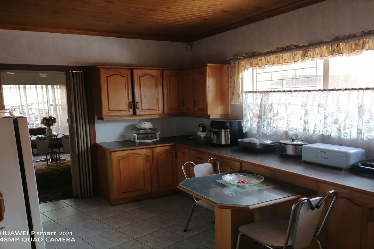 A functional kitchen featuring traditional timber cabinetry, tiled flooring, and a wood-paneled ceiling, offering a classic layout with ample counter space.