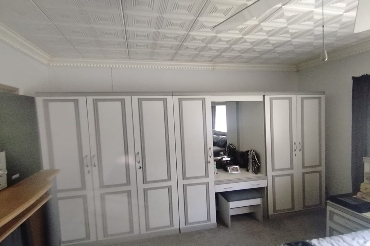 A bedroom featuring a large, built-in wardrobe unit with an integrated vanity and decorative ceiling tiles.