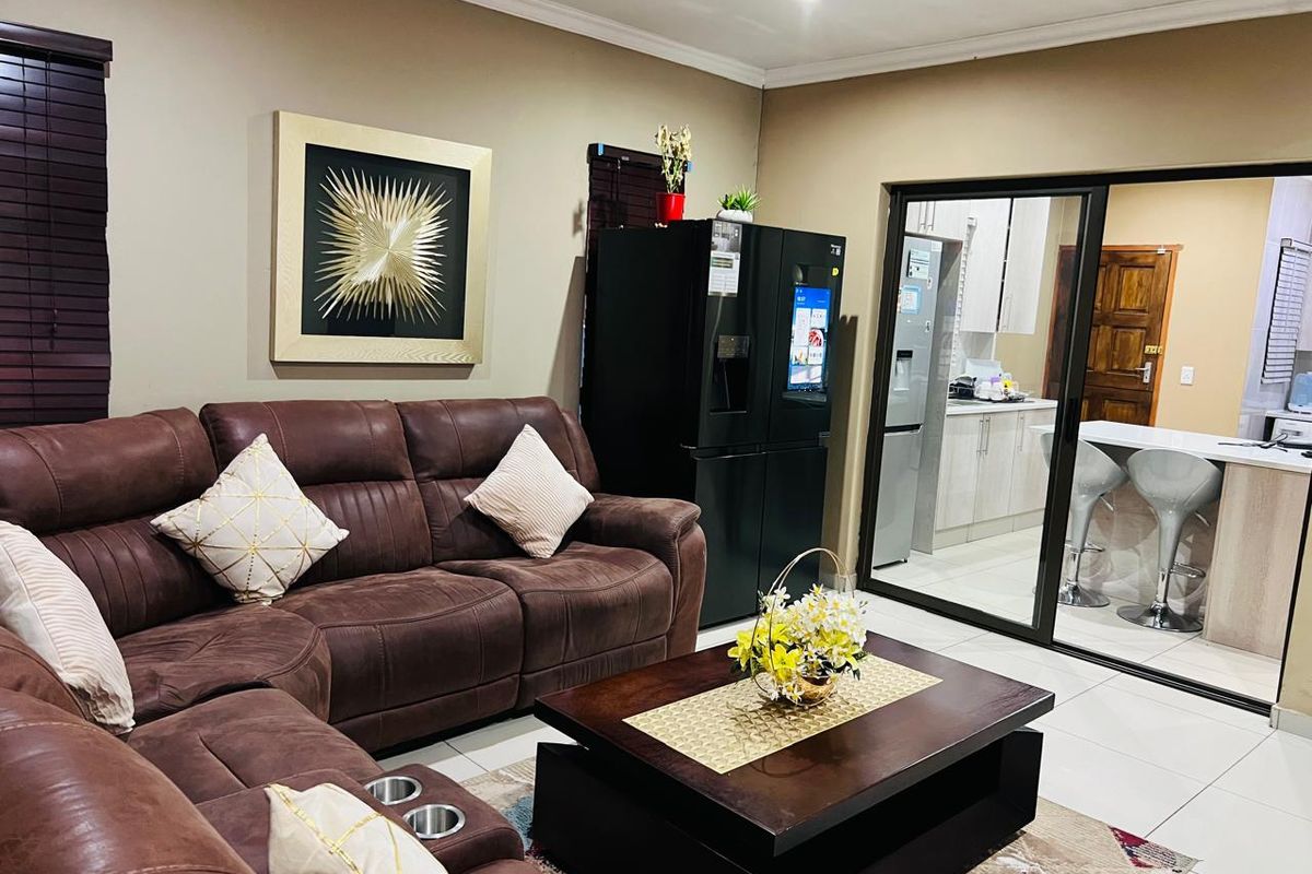 A comfortable living room featuring tiled flooring and sliding glass doors that provide a clear view into the adjacent modern kitchen area.