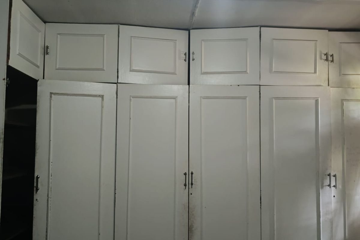 Built-in floor-to-ceiling white cabinetry providing extensive storage, featuring multiple doors and overhead compartments.