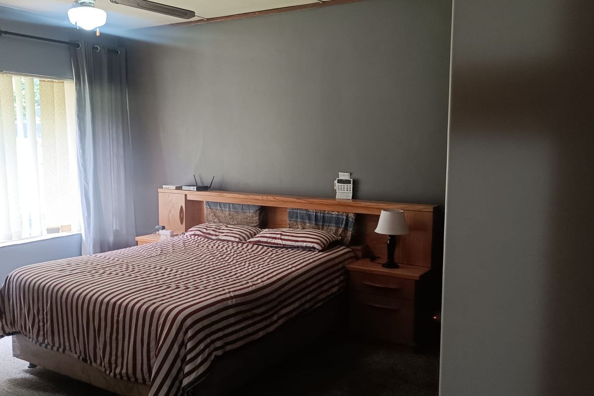A bedroom featuring a built-in wooden headboard with integrated bedside tables and a ceiling fan.