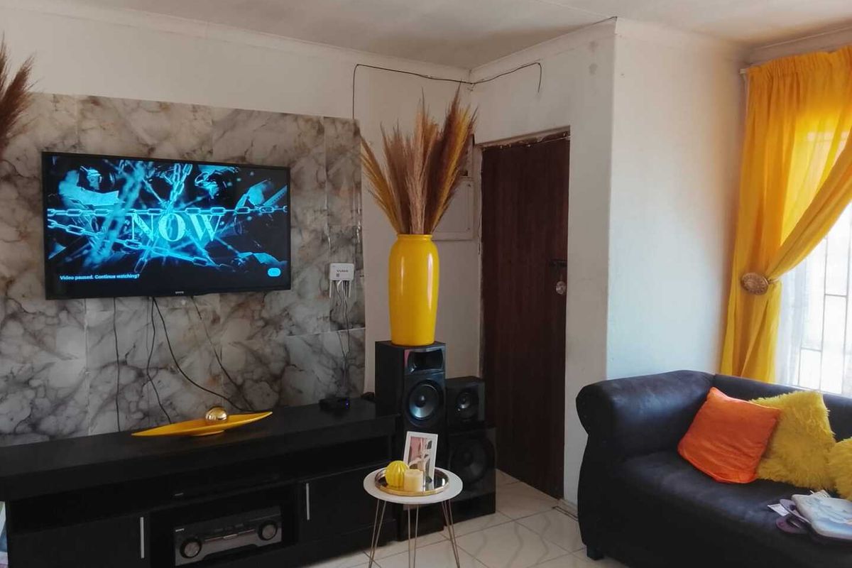 A living room featuring a marble-effect feature wall, tiled flooring, and a standard doorway.