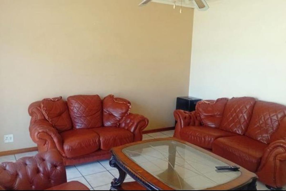 A living room featuring tiled flooring and a ceiling fan, providing a functional and neutral space for relaxation.