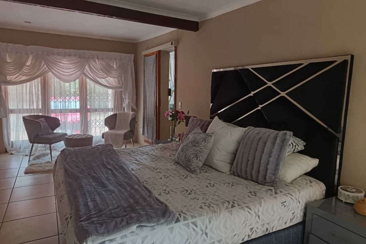 Spacious bedroom featuring tiled flooring, large windows with security gates, and a neutral color palette, offering a comfortable and functional living space.
