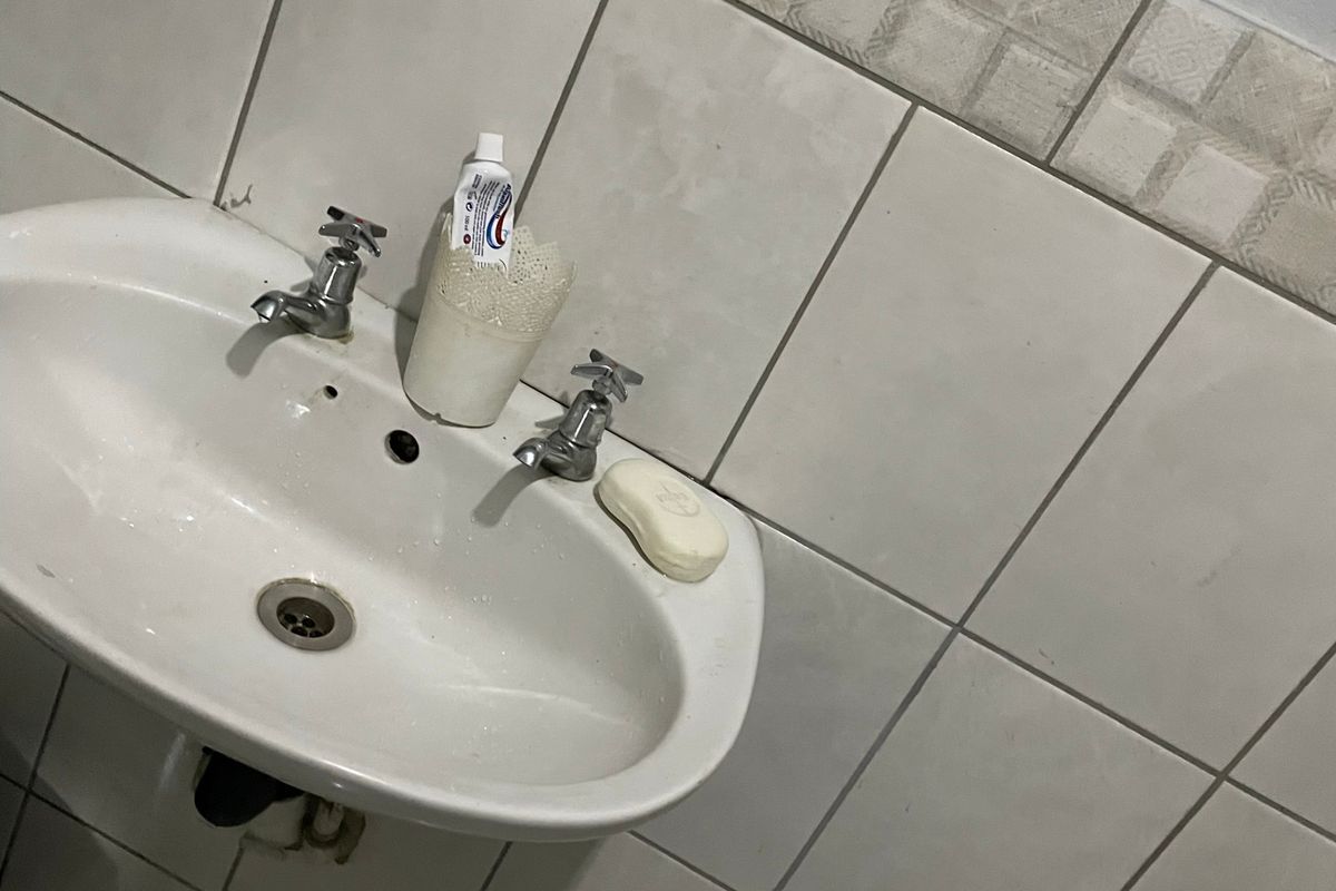 A wall-mounted bathroom basin featuring dual taps and tiled splashback with decorative border detailing.
