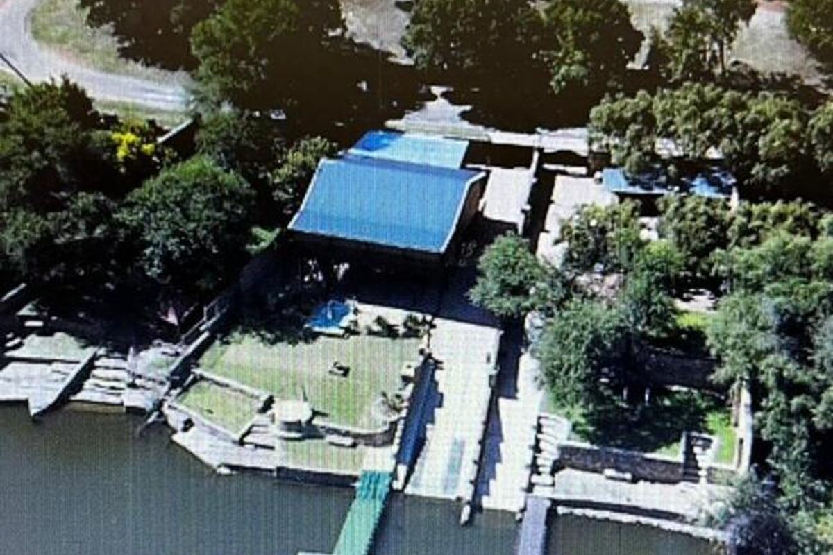 Aerial view of a waterfront property featuring a private jetty, boat ramp, landscaped garden, and direct access to the water.