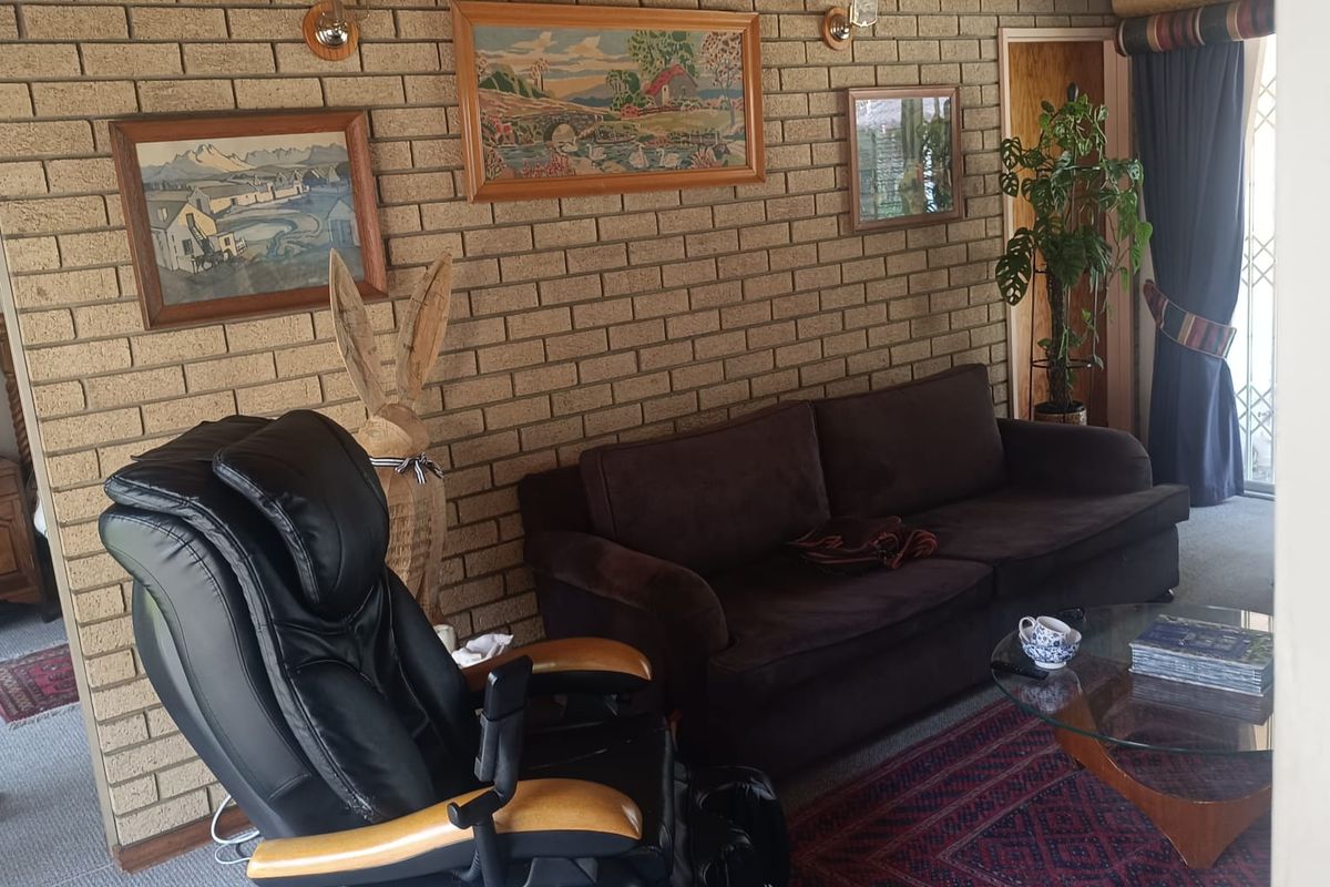 A living room featuring exposed brick walls, timber ceiling paneling, and carpeted flooring, providing a traditional and cozy atmosphere.