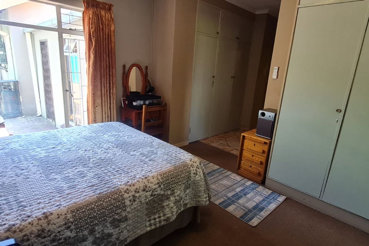 A bedroom featuring built-in cupboards, carpeted flooring, and a glass sliding door providing access to an outdoor patio area.