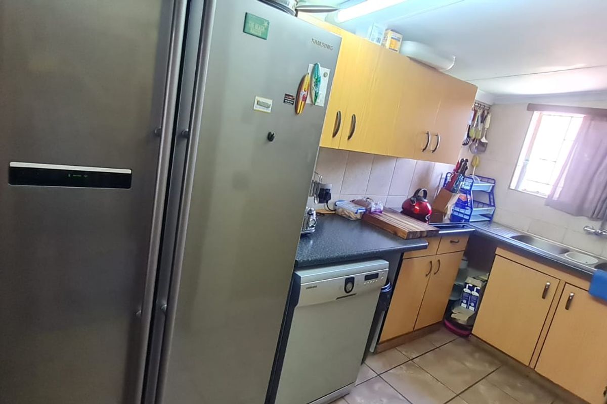 Functional kitchen featuring light wood-tone cabinetry, dark laminate countertops, a double stainless steel sink, and integrated dishwasher space.
