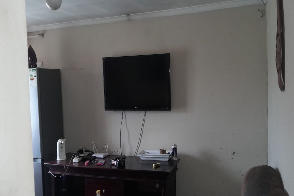 A view of a living area featuring a wall-mounted television and a dark wood console table.