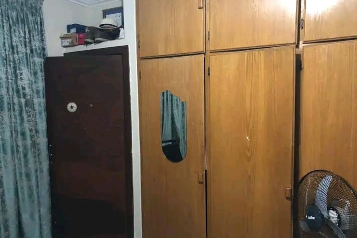 Bedroom featuring floor-to-ceiling built-in wooden cupboards with integrated mirror detail and a standard interior door.