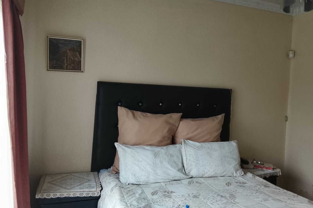 A bedroom featuring decorative ceiling coving and a window with curtain tracks.