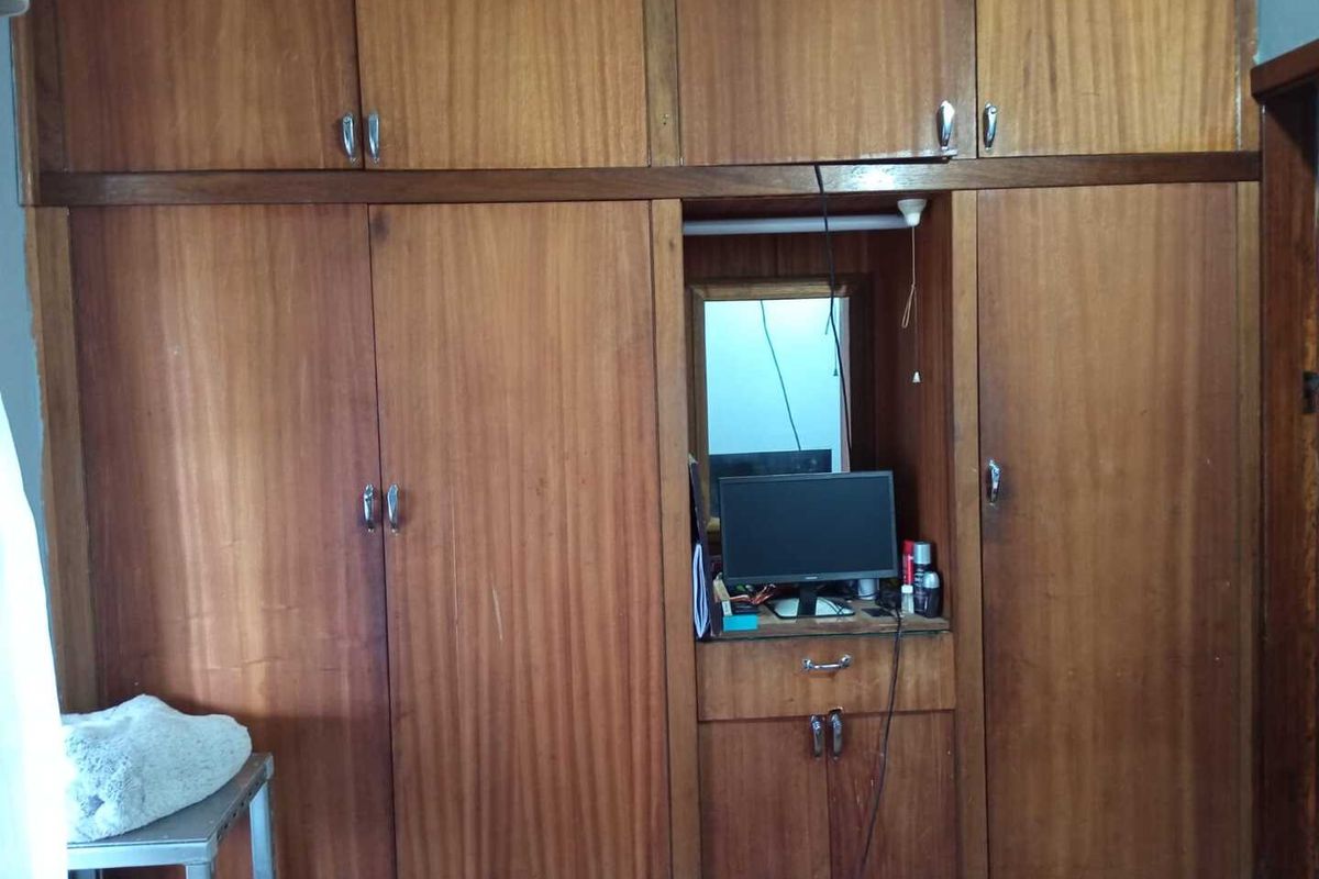 A bedroom featuring extensive floor-to-ceiling built-in wooden cabinetry with integrated storage and a central vanity area.
