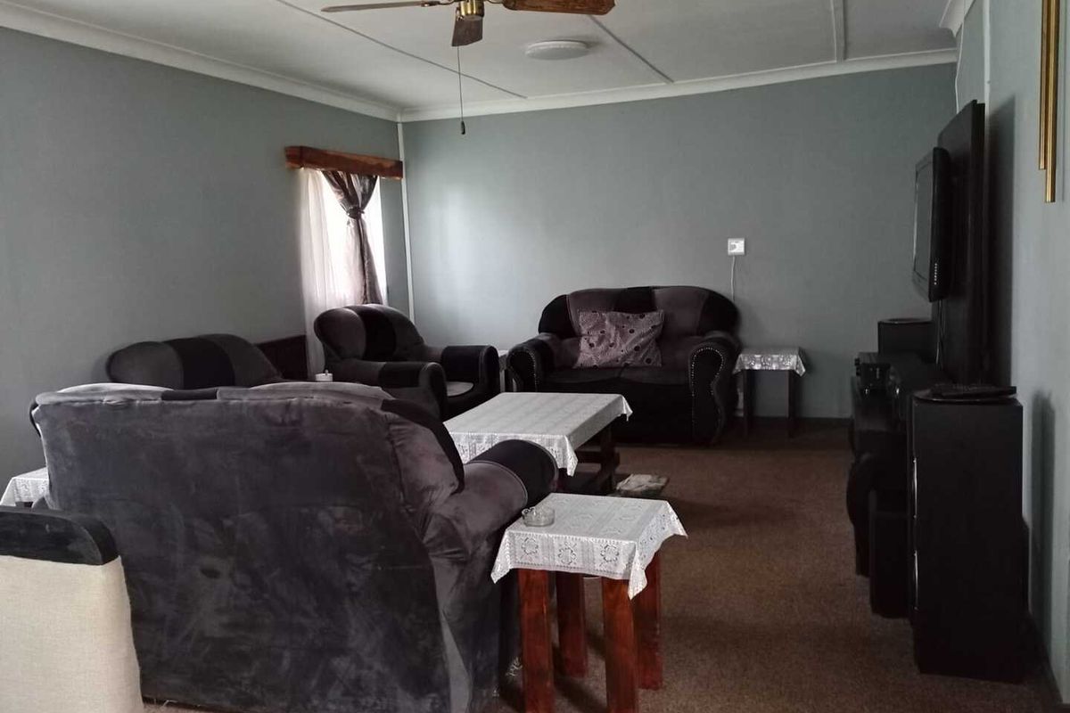 A spacious living room featuring neutral wall tones, a ceiling fan, and carpeted flooring, providing a comfortable and functional area for relaxation.
