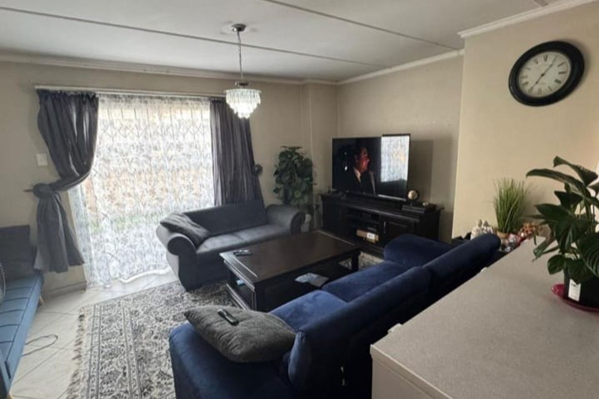 A comfortable living room featuring tiled flooring, a ceiling-mounted light fixture, and large sliding glass doors that provide access to the exterior.