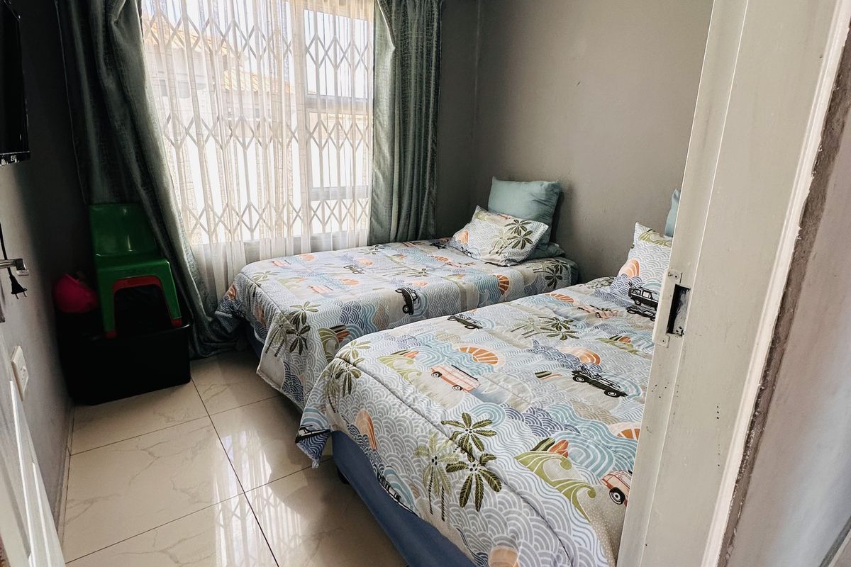 A compact bedroom featuring tiled flooring, a window with security gate, and neutral wall finishes.