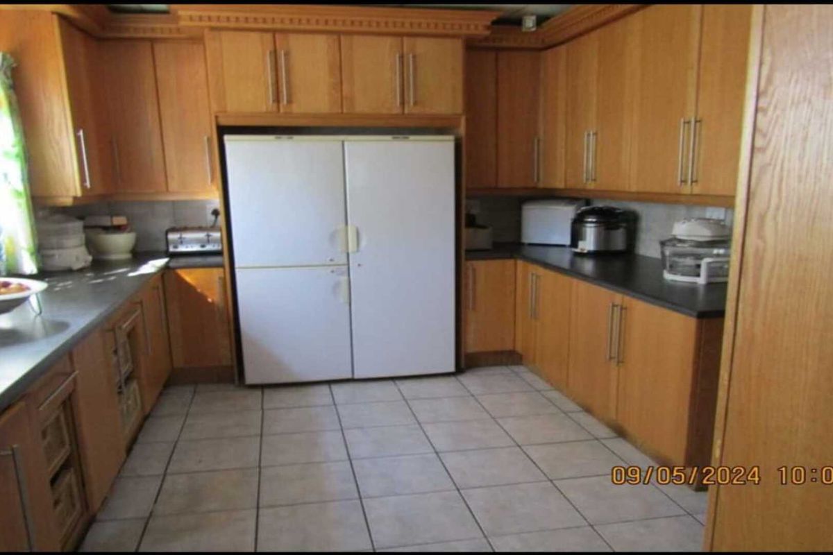 A functional kitchen featuring wood-finish cabinetry, dark countertops, and tiled flooring, providing ample storage and workspace for daily meal preparation.