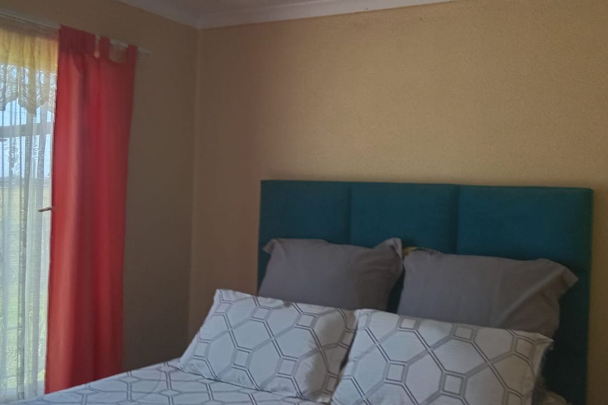 A bedroom featuring a large window with natural light, neutral wall finishes, and a standard layout suitable for a comfortable sleeping space.