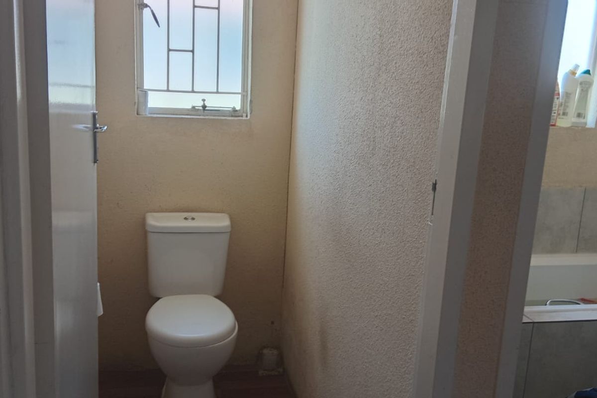 A functional bathroom featuring a standard toilet and a built-in bathtub with tiled surround, requiring cosmetic updates to modernize the space.